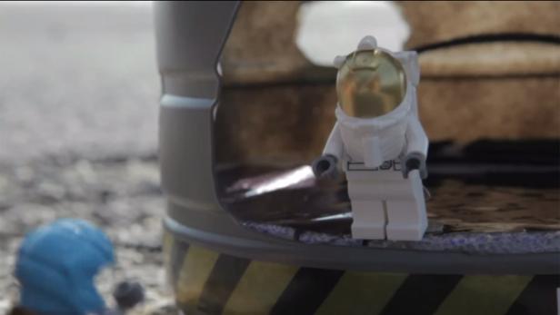 Ein Lego-Astronaut steht neben einem beschädigten Raumschiff.