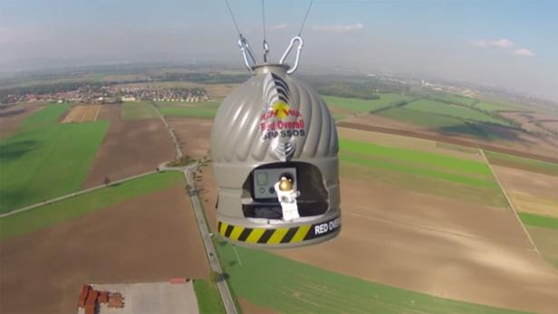 Ein „Red Overall Spassos“-Gefährt schwebt über Feldern und einer Straße.