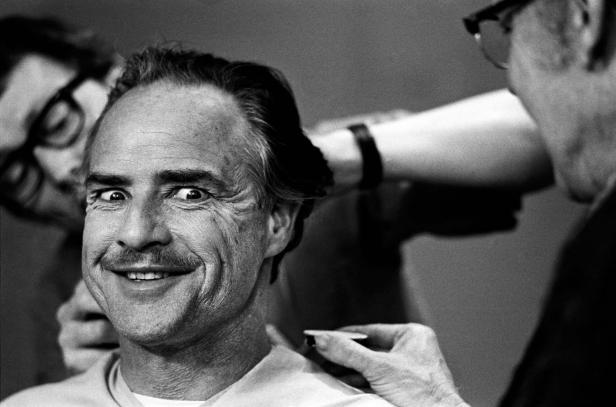 Marlon Brando wird von Maskenbildnern geschminkt.