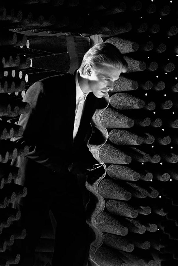 Ein Mann im Anzug steht in einem schalltoten Raum mit kegelförmigen Absorbern.