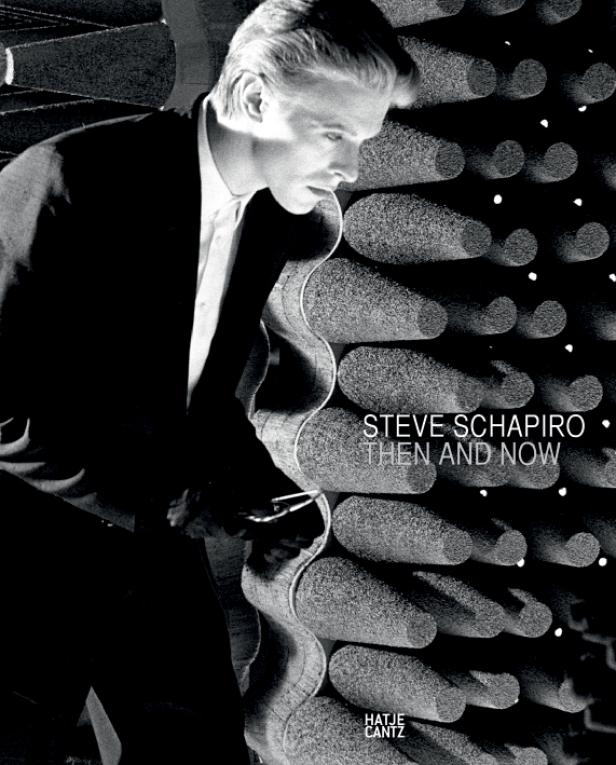 Das Cover des Buches „Steve Schapiro: Then and Now“ zeigt einen Mann im Anzug vor einer Wand mit zylinderförmigen Elementen.