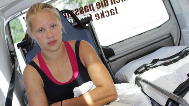 Eine junge Frau sitzt in einem Krankenwagen.