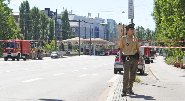 Eine Polizistin steht an einer abgesperrten Straße, im Hintergrund ein Feuerwehrauto und ein Bagger.