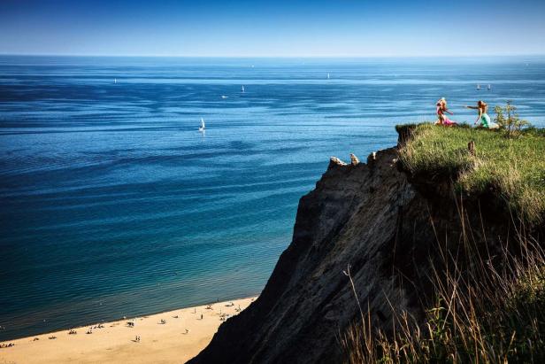 Zwei Frauen stehen auf einer Klippe mit Blick auf einen Strand und das Meer.