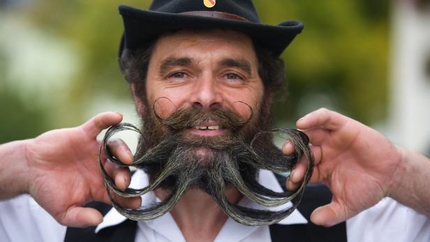 Ein Mann mit Hut präsentiert seinen kunstvoll gezwirbelten Bart.