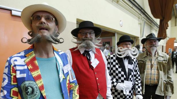 Eine Gruppe Männer mit aufwendigen Bärten und Schnurrbärten bei einem Wettbewerb.