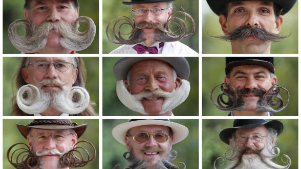 Neun Männer mit aufwendig gestylten Bärten und Schnurrbärten posieren für ein Gruppenfoto.