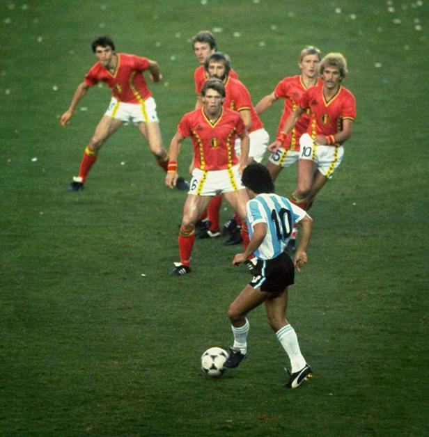 Ein Fußballspieler mit der Nummer 10 dribbelt den Ball, umgeben von belgischen Verteidigern.