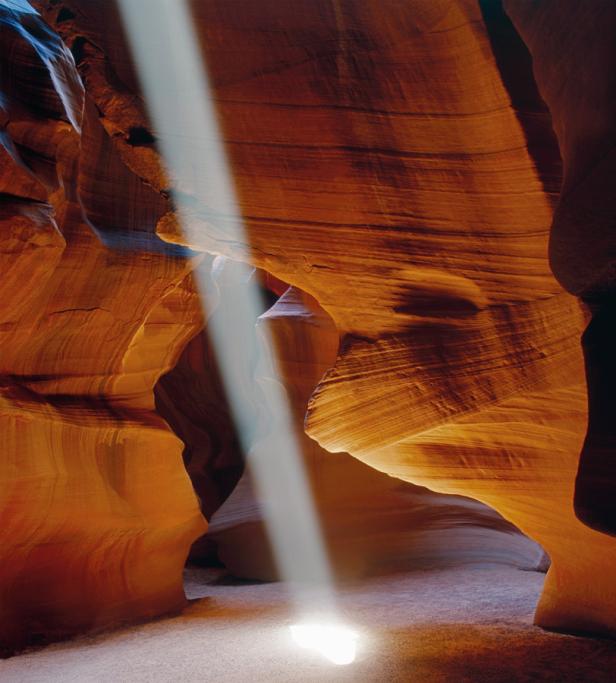 Ein Lichtstrahl fällt in eine orangefarbene Felsformation.