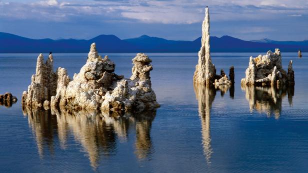 Tuffsteinformationen ragen aus dem ruhigen Wasser eines Sees auf.