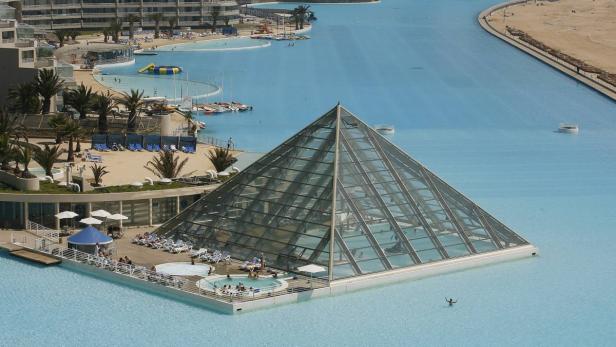 Eine große, glasüberdachte Pyramide steht inmitten eines riesigen Pools in einem Resort.