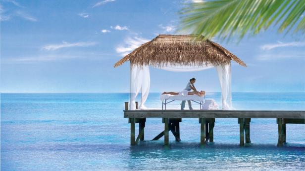 Eine Frau erhält eine Massage in einem Strandpavillon auf dem Wasser.