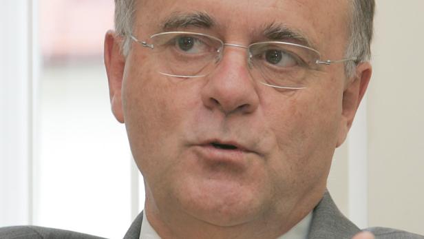 Ein Mann mit Brille und grauem Haar spricht.