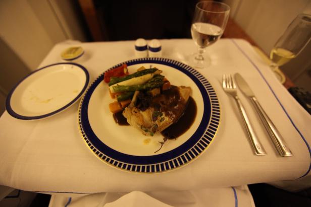 Ein Teller mit Fleisch, Gemüse und Soße auf einem gedeckten Tisch.