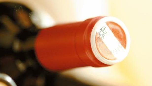 Nahaufnahme des Halses einer Weinflasche mit roter Kapsel.