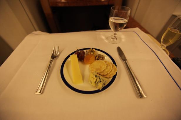 Ein Teller mit Käse, Crackern, Nüssen und Obst auf einem gedeckten Tisch.