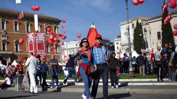 Eine Menschenmenge demonstriert mit roten Ballons und Fahnen der CGIL auf einem belebten Platz.
