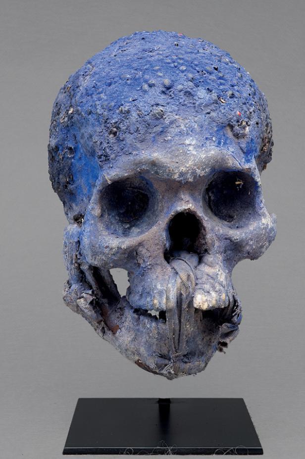 Ein blauer Schädel steht auf einem schwarzen Sockel.