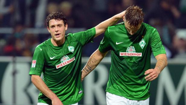 Ein Fußballspieler tröstet einen anderen Spieler mit der Hand auf dem Kopf.