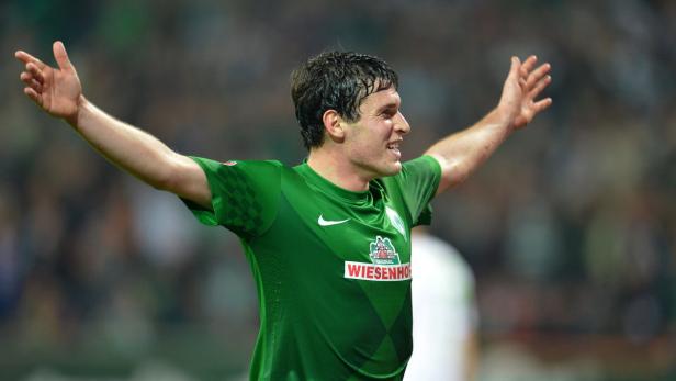 Ein Fußballspieler von Werder Bremen jubelt mit erhobenen Armen.