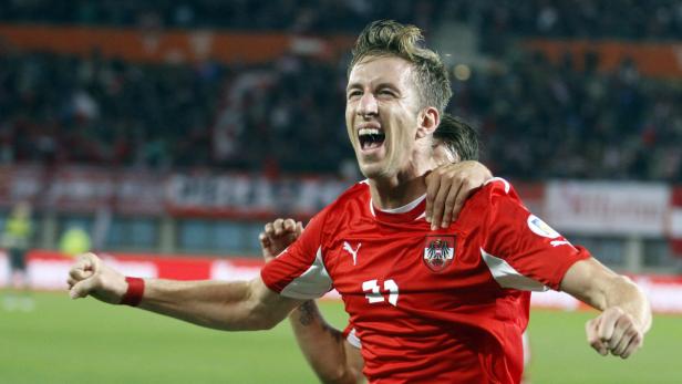 Ein jubelnder österreichischer Fußballspieler im roten Trikot.