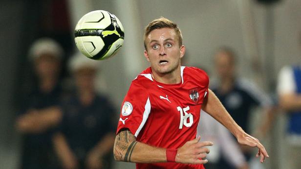 Ein österreichischer Fußballspieler mit der Nummer 15 blickt auf einen Fußball.