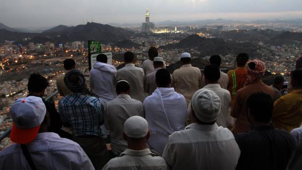 Eine Gruppe von Menschen blickt auf die Stadt Mekka mit der Moschee al-Haram im Hintergrund.