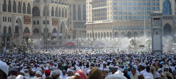 Eine große Menschenmenge versammelt sich in Mekka vor historischen Gebäuden und Ventilatoren.