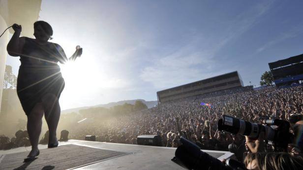 Eine Sängerin tritt vor einer großen Menschenmenge auf einer Bühne auf.