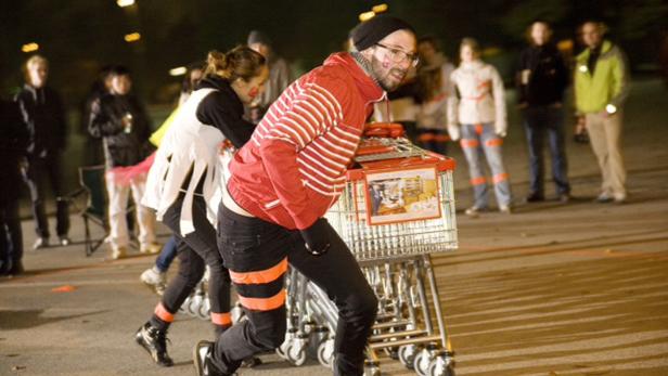 Eine Gruppe von Menschen zieht Einkaufswagen bei einem ungewöhnlichen Rennen.