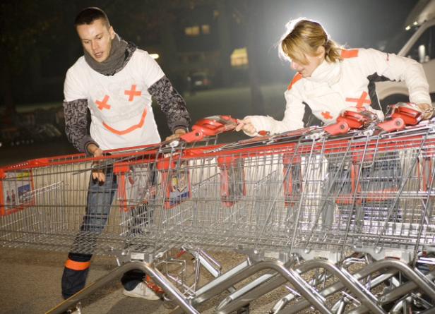 Ein Mann und eine Frau schieben gemeinsam eine Reihe von Einkaufswagen.