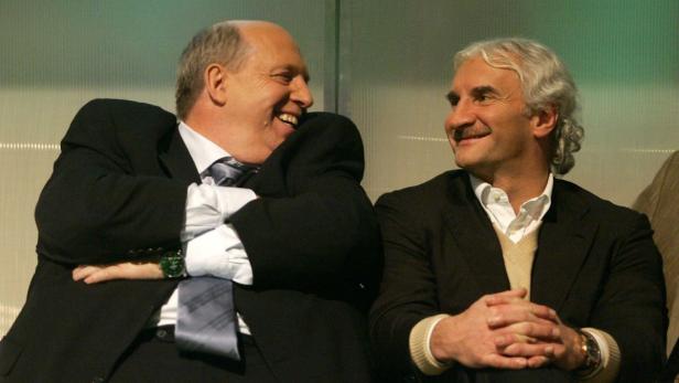 Zwei Männer in Anzügen unterhalten sich lächelnd.