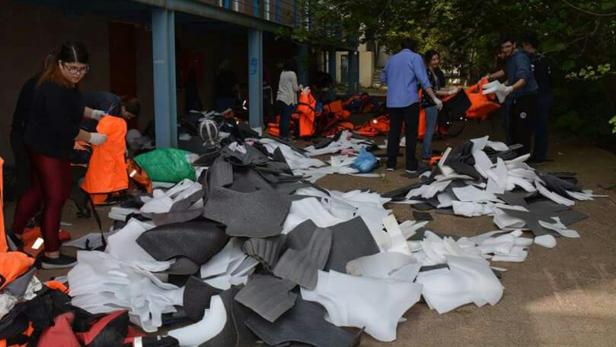 Eine Gruppe von Menschen sortiert Schwimmwesten und Schaumstoffteile im Freien.