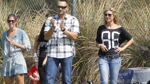 Heidi Klum und andere Zuschauer stehen im Freien und schauen zu.