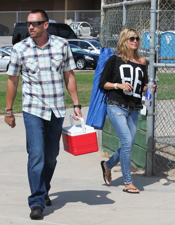 Heidi Klum und ein Mann mit einer Kühlbox gehen auf einem Bürgersteig entlang.