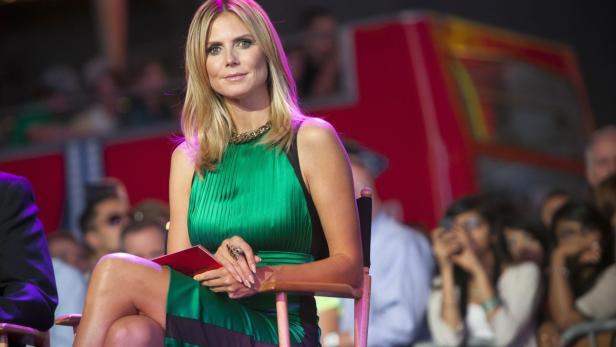 Heidi Klum sitzt in einem grünen Kleid vor Publikum.