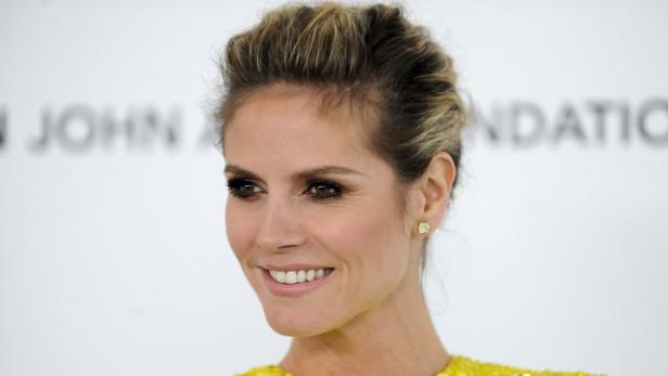 Ein Porträt von Heidi Klum mit blonden Haaren und einem gelben Kleid.