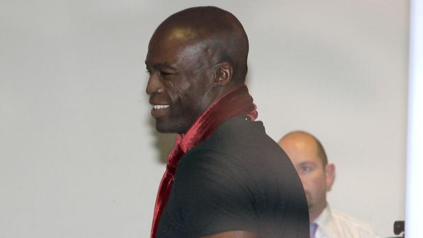 Der Sänger Seal mit einem roten Schal um den Hals lächelt.