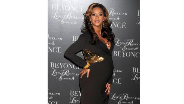 Eine schwangere Beyoncé in einem schwarzen Kleid auf einem Event.