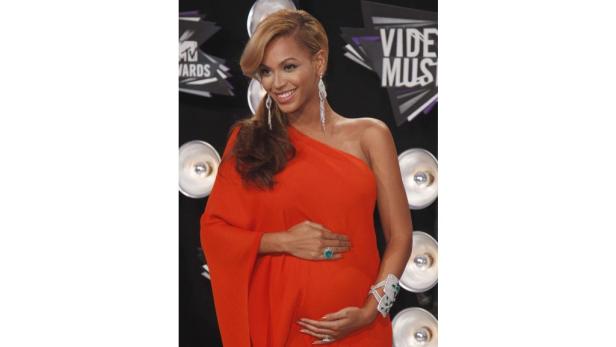 Beyoncé in einem roten Kleid bei den MTV Video Music Awards, ihre Hände auf ihrem Bauch.