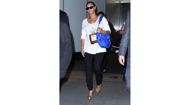 Beyoncé trägt eine weiße Bluse, schwarze Hose, Sonnenbrille und eine blaue Tasche.