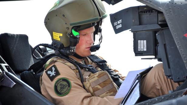 Prinz Harry im Cockpit eines Apache-Hubschraubers, während er Dokumente prüft.