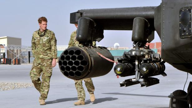 Prinz Harry in Militärkleidung geht an einem Apache-Kampfhubschrauber vorbei.