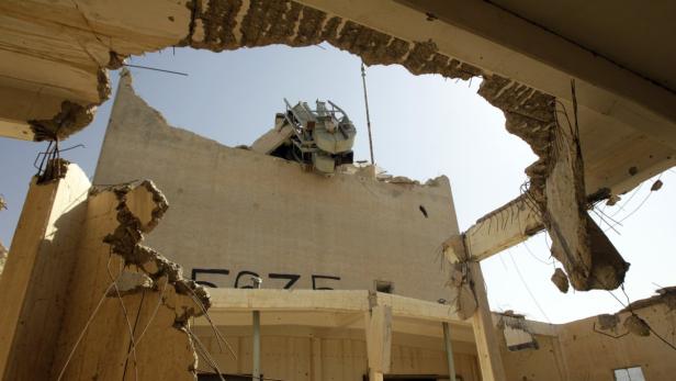 Ein zerstörtes Gebäude mit freiliegenden Trümmern und einem beschädigten Kran auf dem Dach.