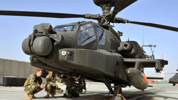 Zwei Soldaten inspizieren einen Apache-Kampfhubschrauber.