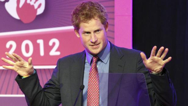 Prinz Harry hält eine Rede vor einem Banner mit der Aufschrift „2012“.