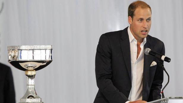 Prinz William spricht bei einer Veranstaltung neben einer silbernen Trophäe.