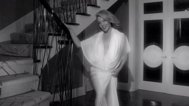 Kylie Minogue in einem weißen Kleid auf einer Treppe.