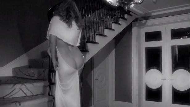 Eine Frau in einem weißen Kleid steht vor einer Treppe.