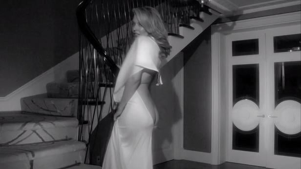 Eine Frau in einem weißen Kleid steht auf einer Treppe und blickt über ihre Schulter.